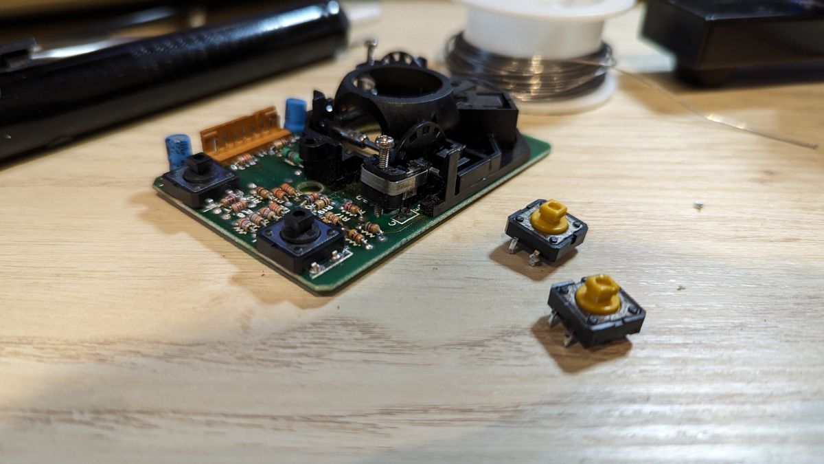 The mouse PCB with new buttons mounted, and the old ones alongside